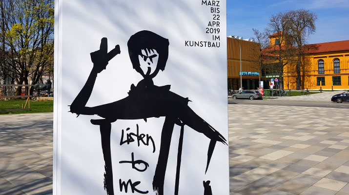 Plakat vor dem Kunstbau am Königsplatz zur Ausstellung Ein prekäres Singspiel von Beate Engl, Leonie Felle und Franka Kaßner