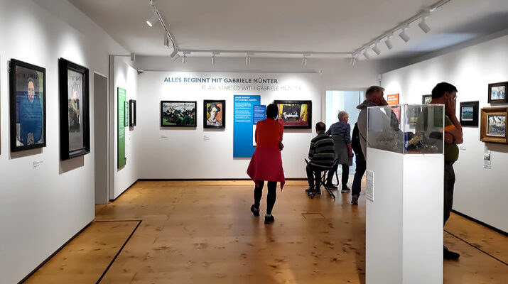 Gemälde und Besucher:inen der Ausstellung Gabriele Münter im Schlosmuseum Murnau