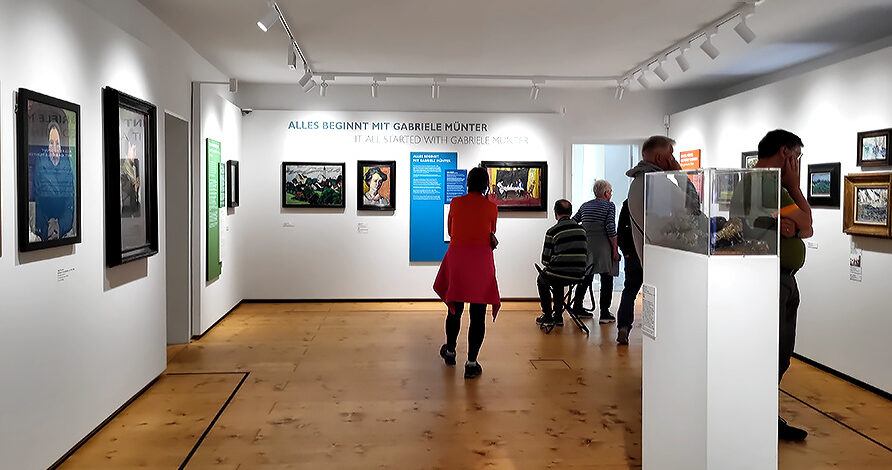 Gemälde und Besucher:inen der Ausstellung Gabriele Münter im Schlosmuseum Murnau