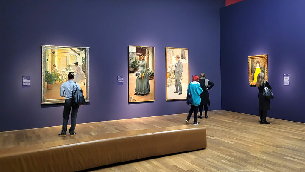 Ausstellungsräume mit Besucher:innen und Gemälden in der Ausstellung Barcelona moderna - von Gaudí bis Picasso in der Kunsthalle München